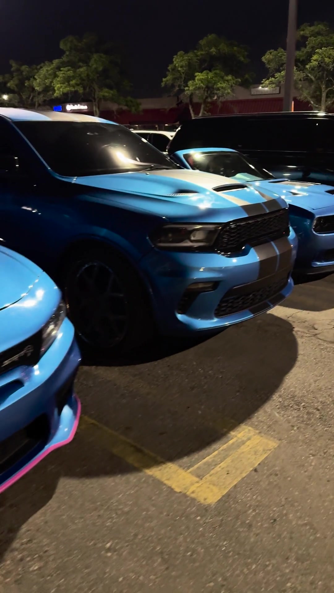 Blue muscle cars together at an evening event